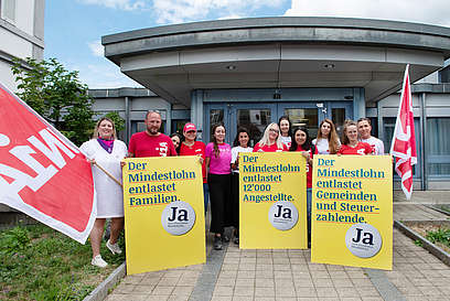 Dépôt de l'initiative sur les salaires minimums à Bâle-Campagne avec des drapeaux et des affiches d'Unia